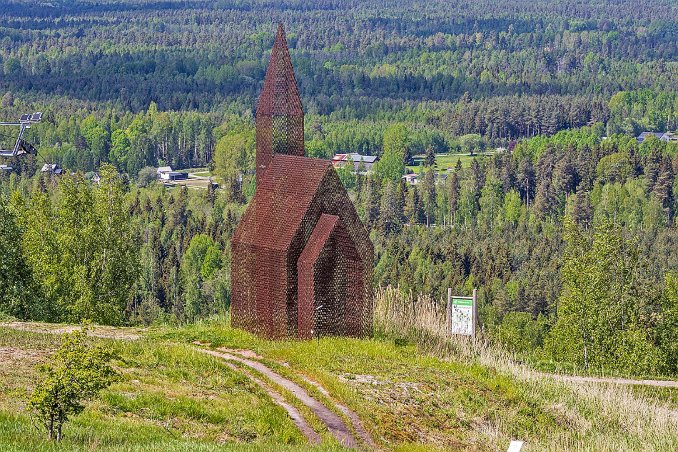 Kyrka på högen Absit omen av Kent Karlsson (2003). Tenik: svetsad sträckmetall. Något som ser ut som en kyrka har vuxit upp och blivit ännu en siluett på högen. Konstnärens...